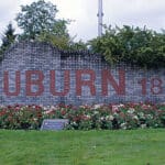 Auburn, Washington city limits sign made of brick with red block letters and a prominent display of roses and green landscaping.