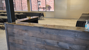 View of meeting room with black table covers gray chairs wood reception counter and hand sanitizer on counter