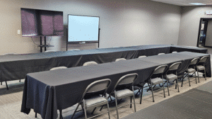 Training room setup with black table covers gray folding chairs wall mounted TV and whiteboard