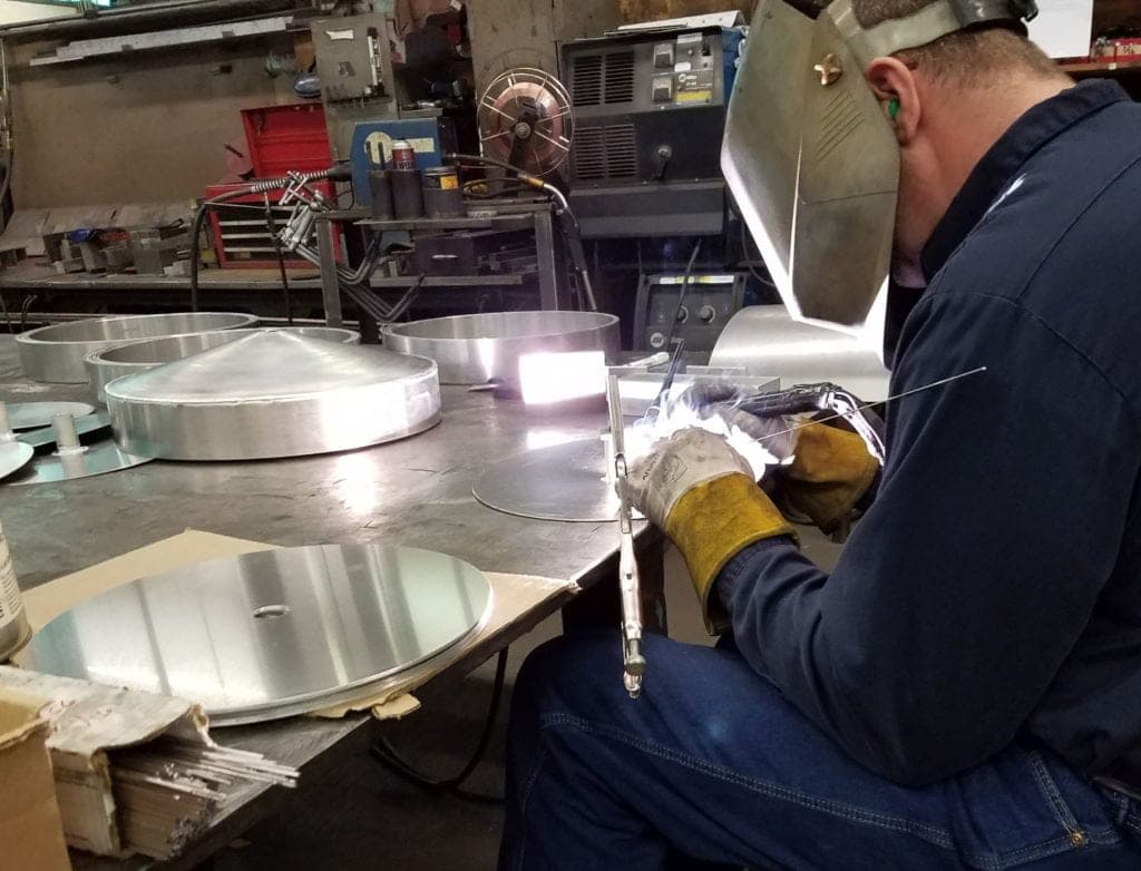 A skilled welder performing precision TIG welding on aluminum components in a Vancouver, WA manufacturing facility.